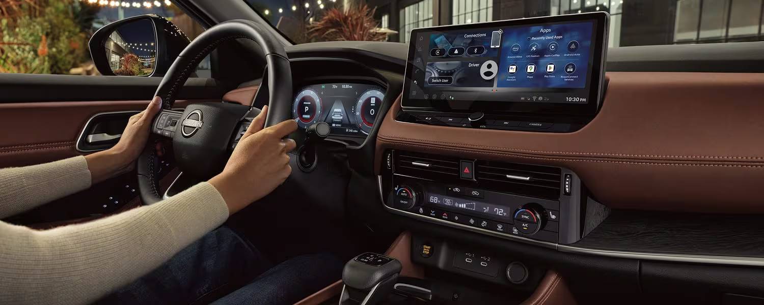 Someone drives a 2026 Nissan Rogue with the assistance of the dashboard touchscreen. Why the Nissan Rogue is the Perfect Road Trip Vehicle at Medicine Hat Nissan in Medicine Hat, AB
