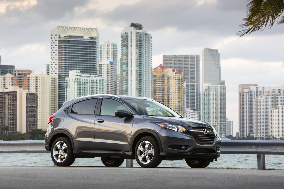 Vue 3/4 latérale du VUS Honda HR-V 2016 garé au bord d'un fleuve et une ville métropolitaine