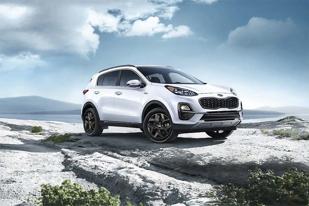Vue 3/4 avant du VUS Kia Sportage 2021 blanc garé sur un grand rocher