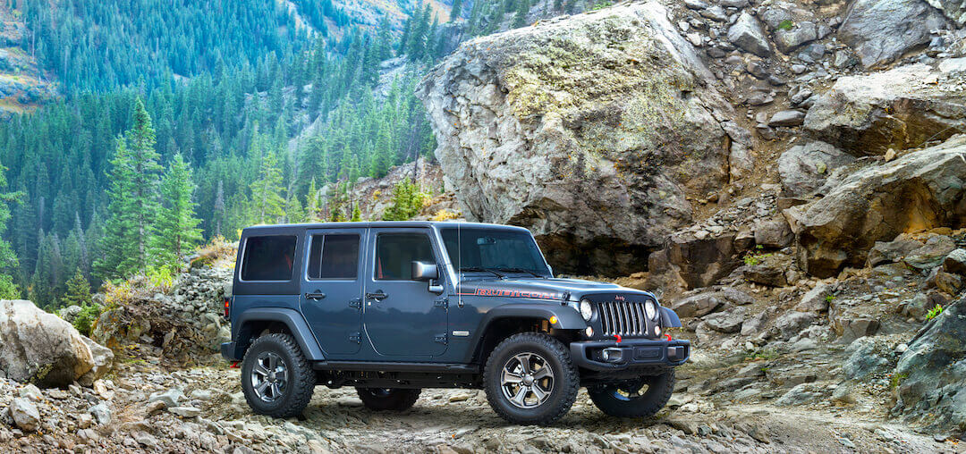 vue latérale 3/4 avant d'un VUS 4x4 Jeep Wrangler JK Rubicon 2018 garé sur des rochers en nature