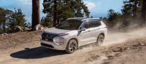 2025 Mitsubishi Outlander PHEV driving down a dirt road