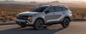 A silver 2026 Kia Sportage parks in front of a hilly off-road landscape. New 2026 Kia Sportage for sale in Miramichi, NB at Miramichi Kia