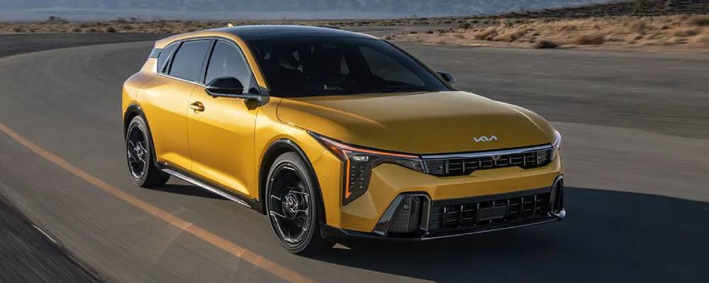 A yellow 2026 Kia K4 Hatchback with a black roof drives along a highway. New 2026 Kia K4 Hatchback & 2026 Kia K4 Sedan vehicle comparison guide at Miramichi Kia in Miramichi, NB