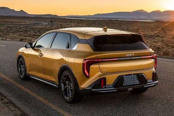 The rear profile of a yellow 2026 Kia K4 Hatchback with a black roof as it drives along a highway. New 2026 Kia K4 Hatchback & 2026 Kia K4 Sedan vehicle comparison guide at Miramichi Kia in Miramichi, NB