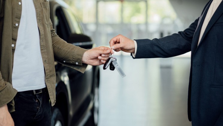Person handing over car keys to another person in dealership