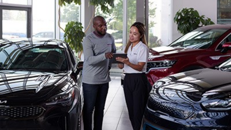 Customer looking at tablet with employee in dealership showroom