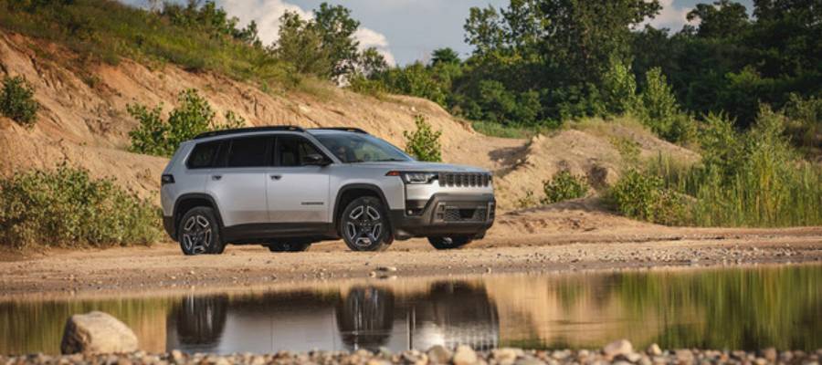 A silver 2026 Jeep Cherokee parked off-road between a cliff and a lake. New 2026 Jeep Cherokee for sale at Orangeville Chrysler Dodge Jeep Ram in Orangeville, ON