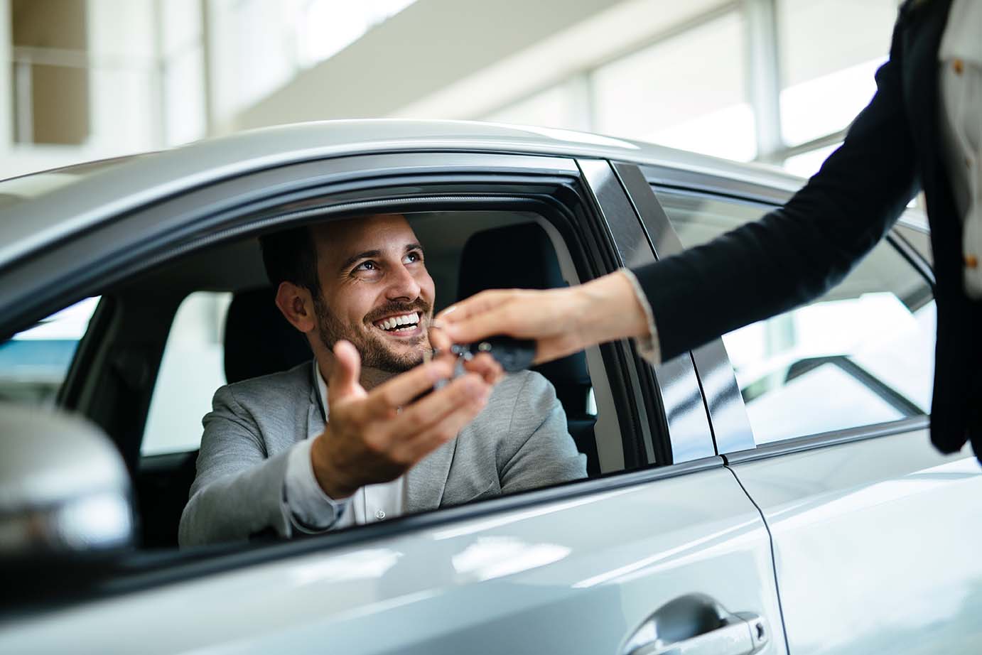 Person handing driver keys as they sit inside vehicle