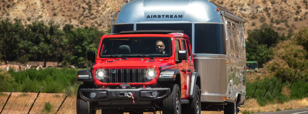 Red Jeep Wrangler Towing a Camper Van