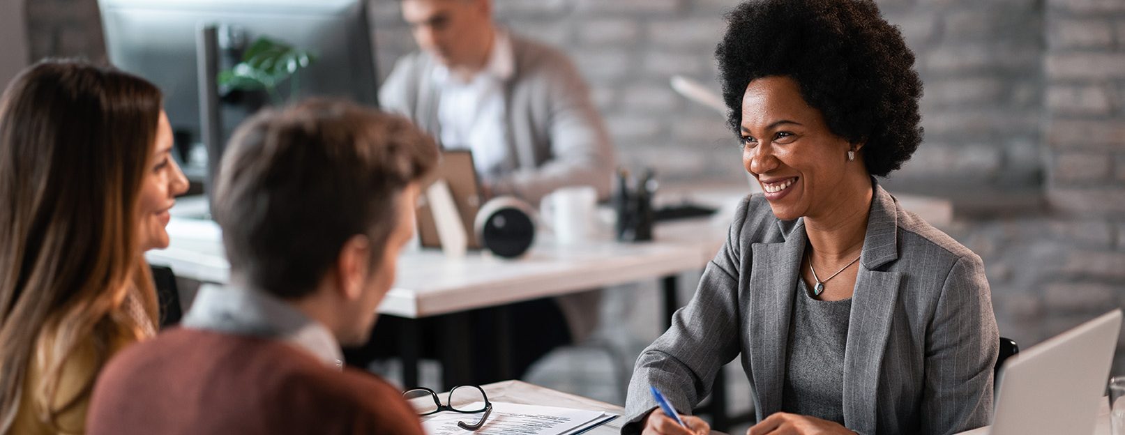 Happy African American financial advisor talking to a couple about their future investment during a meeting in the office.