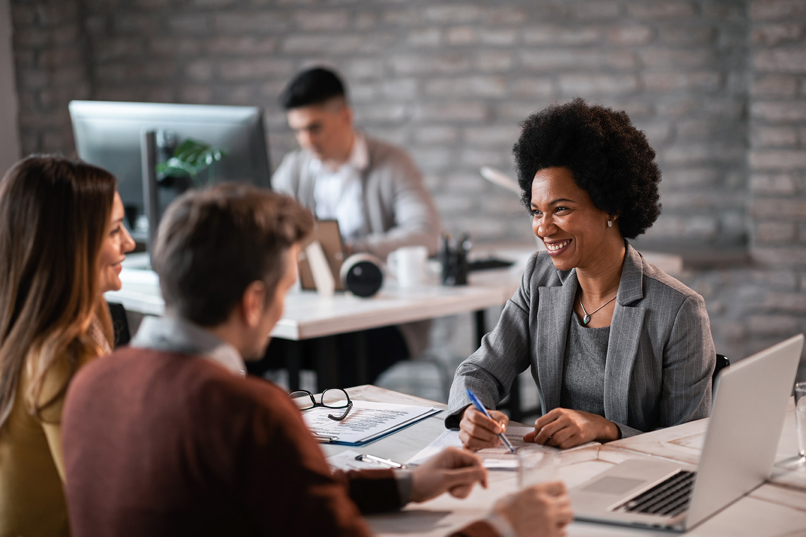 Happy African American financial advisor talking to a couple about their future investment during a meeting in the office