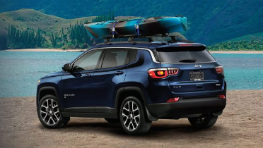 Rear side view of 2021 Jeep Compass in front of water with kayak on the roof