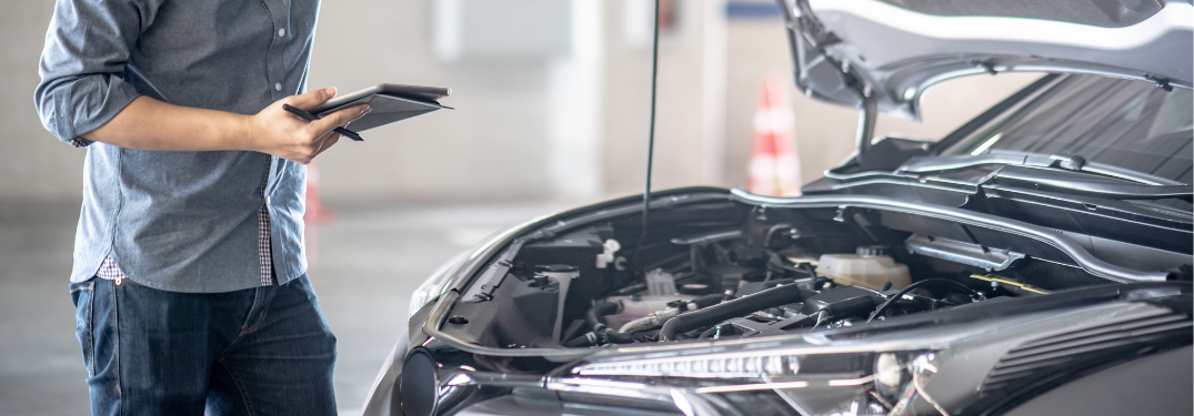 A technician working on a vehicle with the hood open