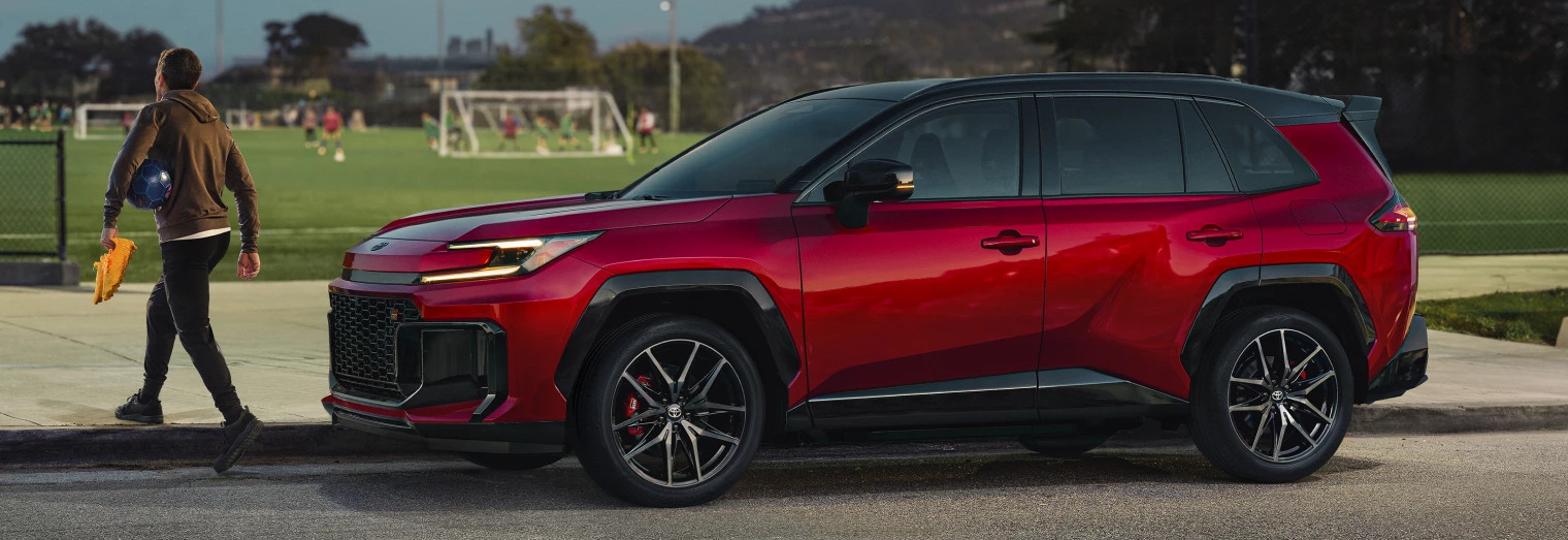 Person walking near 2026 Toyota RAV4 Plug-In Hybrid that's parked by soccer field