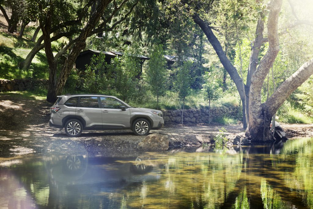 2026 Subaru Forester parked beside a wooded creek, showing its ground clearance and outdoor adventure capability.
