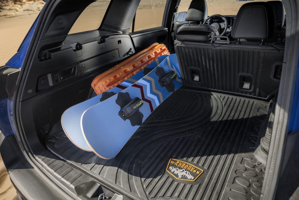 2026 Subaru Outback Wilderness rear cargo area with the seats up, featuring an all‑weather cargo liner and snowboards laid flat inside.