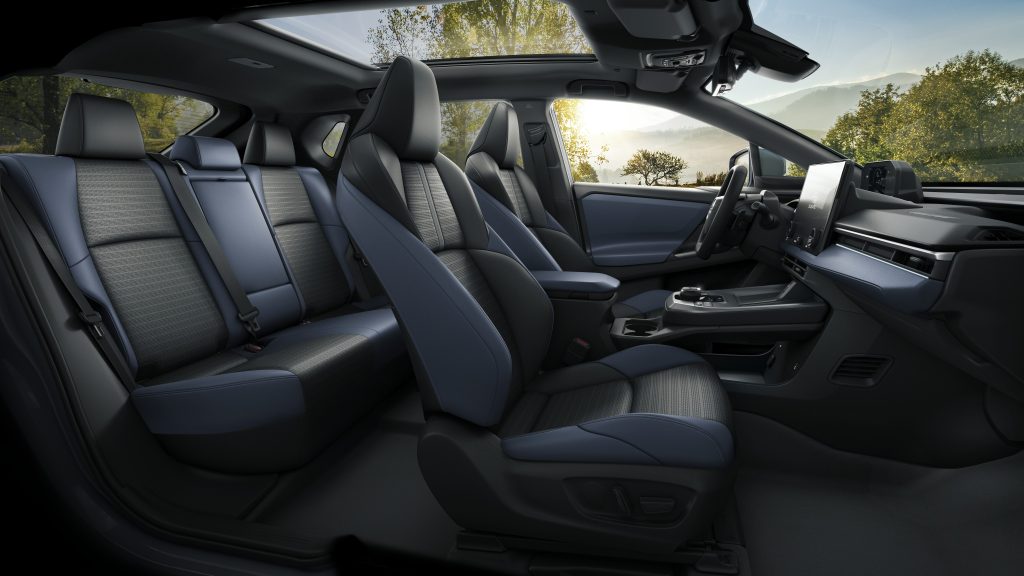 Side view of the 2026 Subaru Solterra interior showing front and rear seats, panoramic glass roof, center touchscreen and modern dash design.