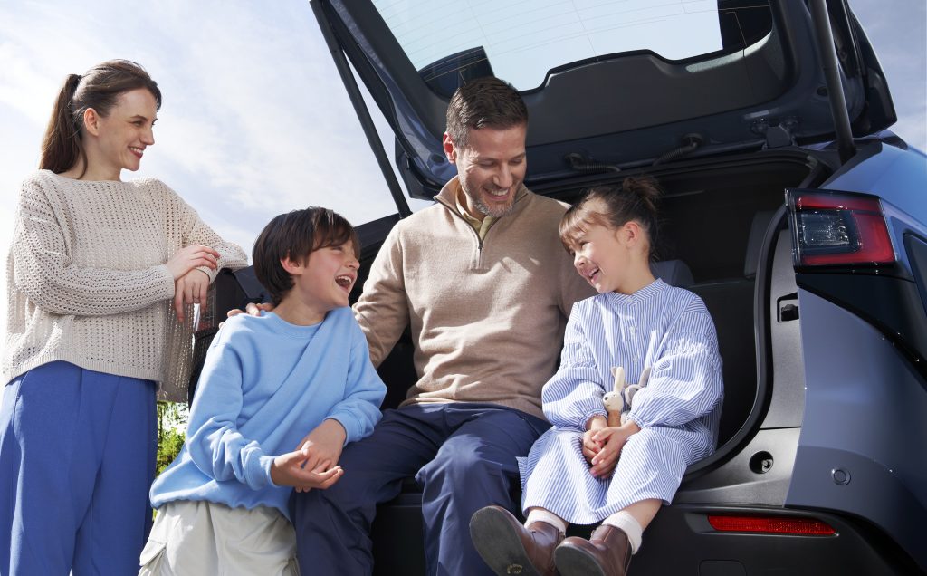 Family relaxing at the open rear of a 2026 Subaru Solterra, children and parents gathered around the cargo area on a sunny day.