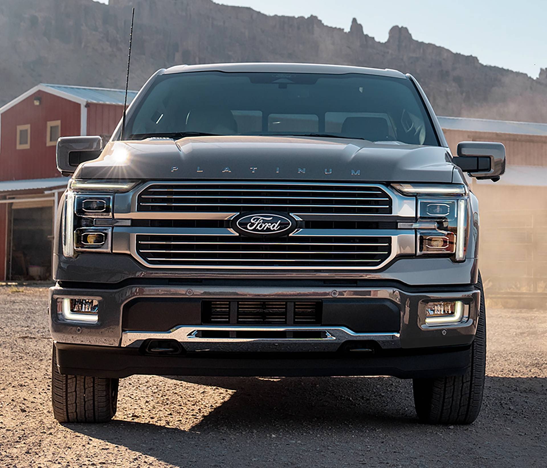 A black 2025 Ford F-150 sits on dirt in front of a ranch