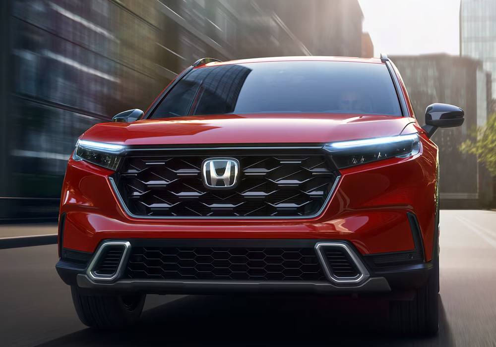 A red 2026 honda cr-v drives through a city