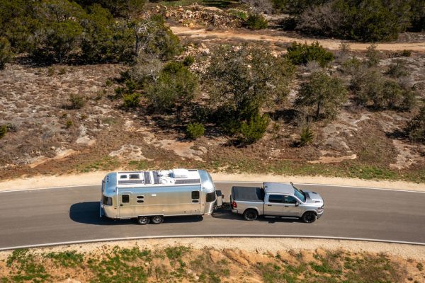 A 2025 Ram 1500 towing a silver trailer on a highway.