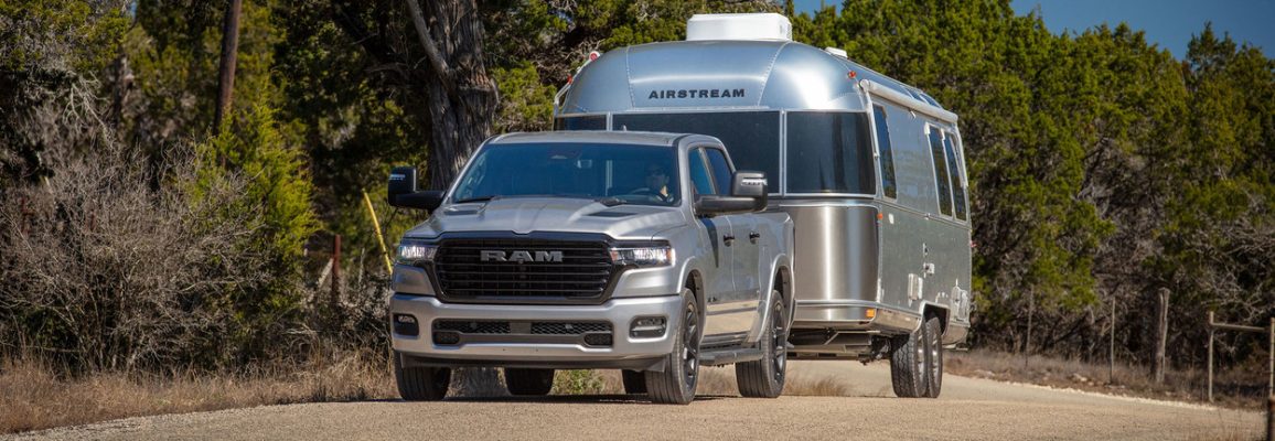 A silver 2025 Ram 1500 tows a trailer.