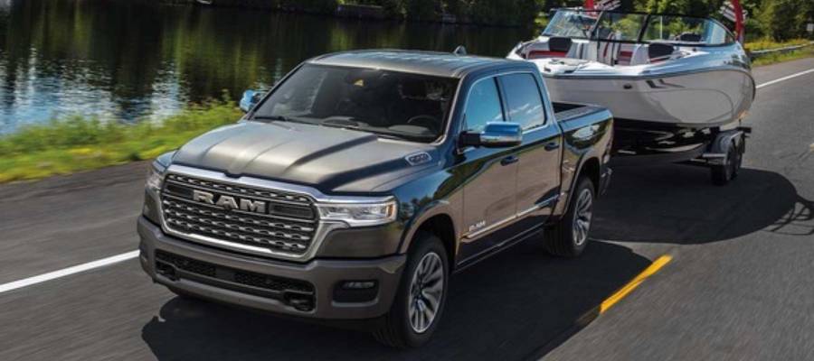 A silver 2026 Ram 1500 pulls a boat alongside a river. 2026 Ram 1500 vehicle comparisons at Tilbury Chrysler in Tilbury, ON