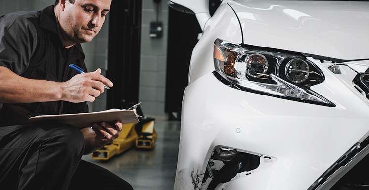 A Lexus-certified technician at Tony Graham Lexus in Ottawa inspects a vehicle in the collision repair bay, ensuring precision and quality craftsmanship during every repair.