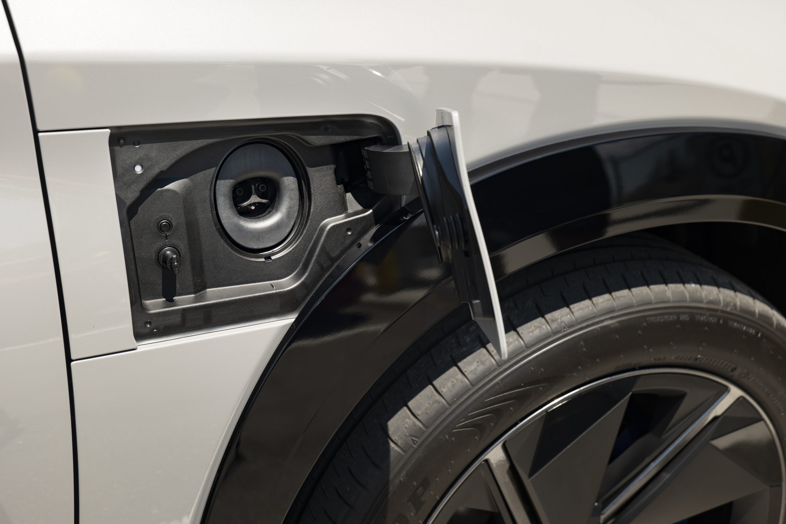 Close-up of the 2026 Lexus RZ 550e F SPORT AWD charging port with the cover open, showing the NACS-compatible connector.