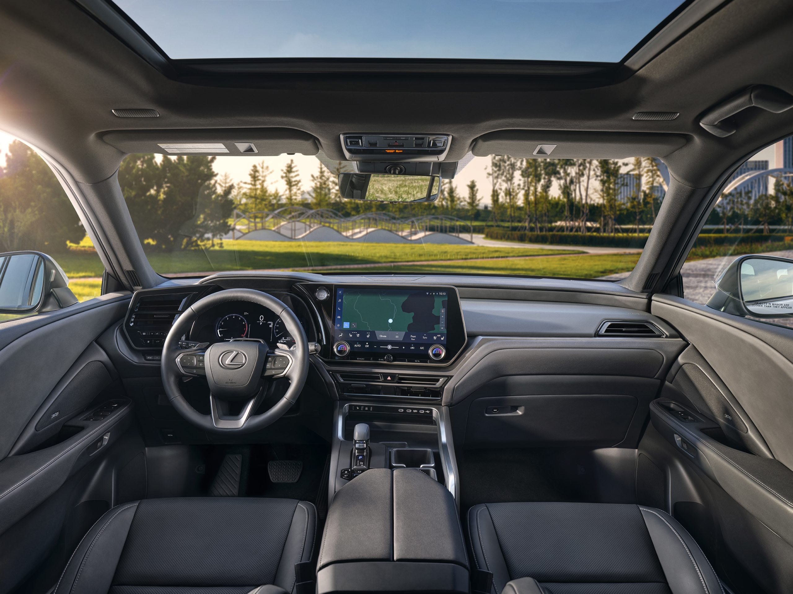 Interior view of the 2026 Lexus TX showcasing the driver’s cockpit, steering wheel, digital dashboard, and 14-inch touchscreen display beneath a panoramic sunroof.