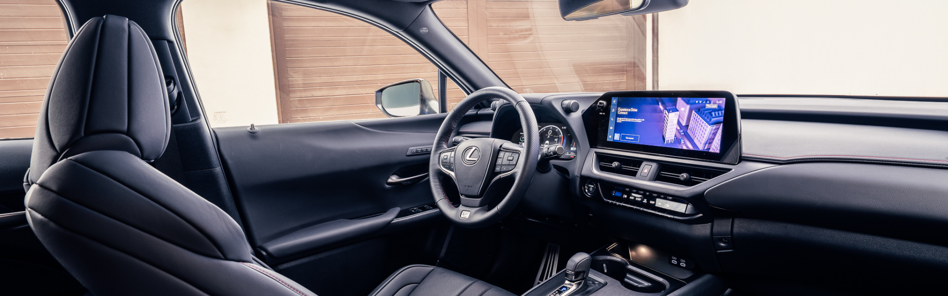 Interior view of a Lexus UX showing the dashboard, steering wheel, front seats, and center infotainment screen