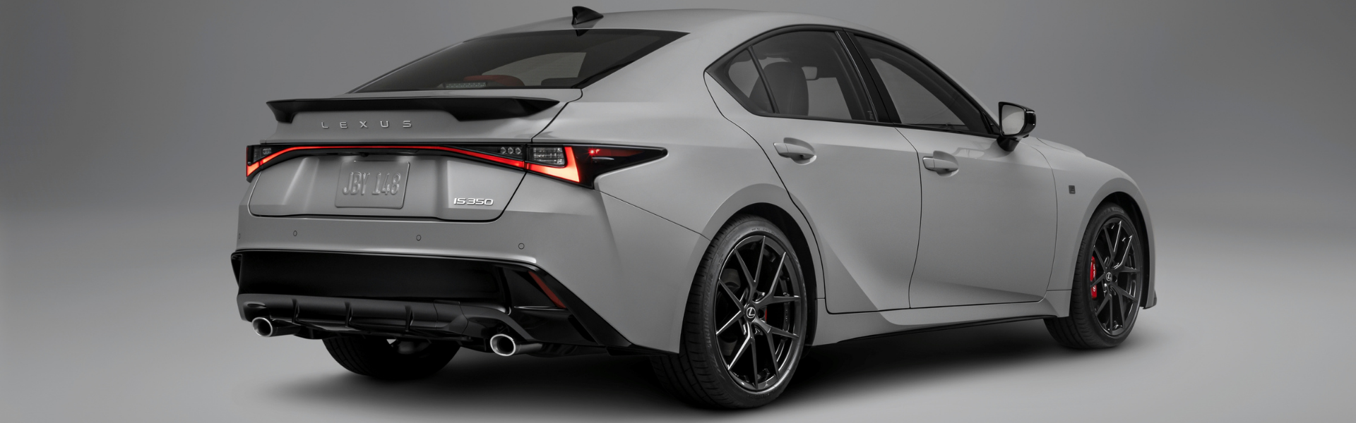 2026 Lexus IS 350 F SPORT in white shown from rear three quarter angle with LED taillights and dual exhaust