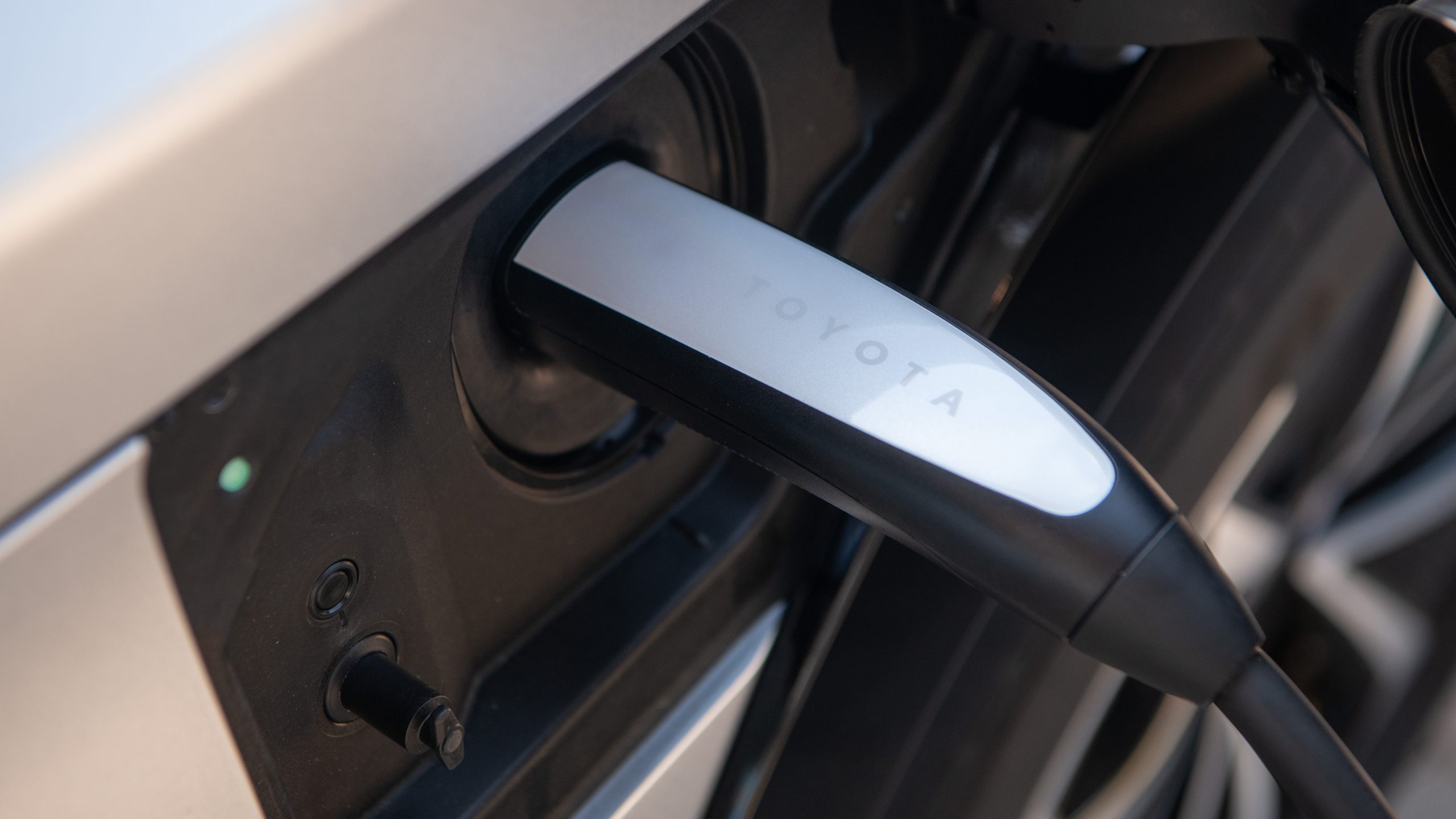Close-up of a Toyota-branded EV charging cable plugged into a vehicle’s charging port.
