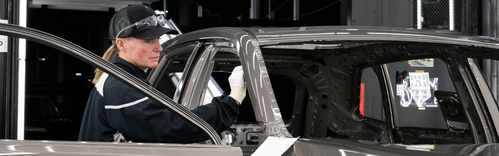 Factory worker inspecting Toyota vehicle body structure during assembly process