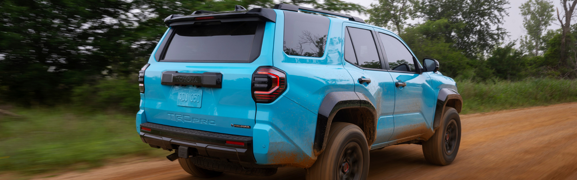 Blue Toyota 4Runner TRD Pro driving on a dirt road with mud on the body