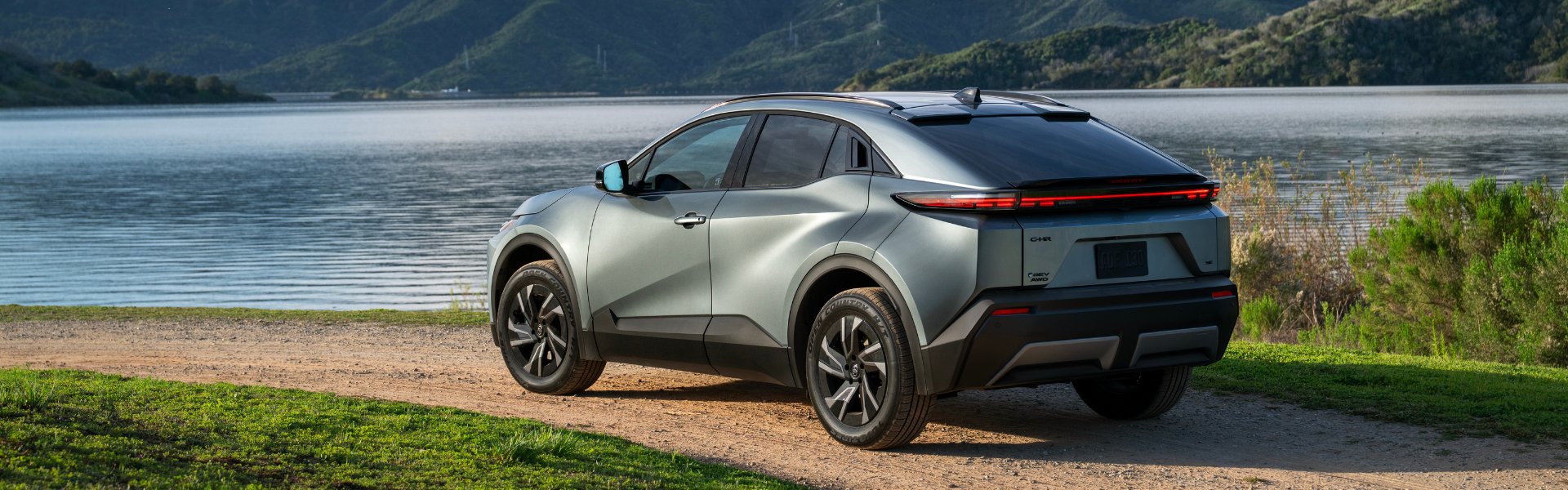 2026 Toyota C-HR rear three-quarter view parked on a dirt road beside a lake