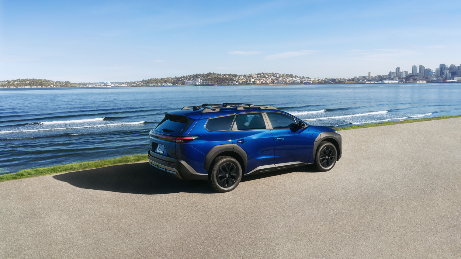 2026 Toyota bZ Woodland rear three-quarter view parked beside an ocean shoreline road