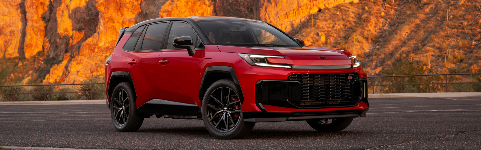 Red 2026 Toyota RAV4 PHEV GR Sport shown from the front three-quarter angle with rocky canyon cliffs in the background