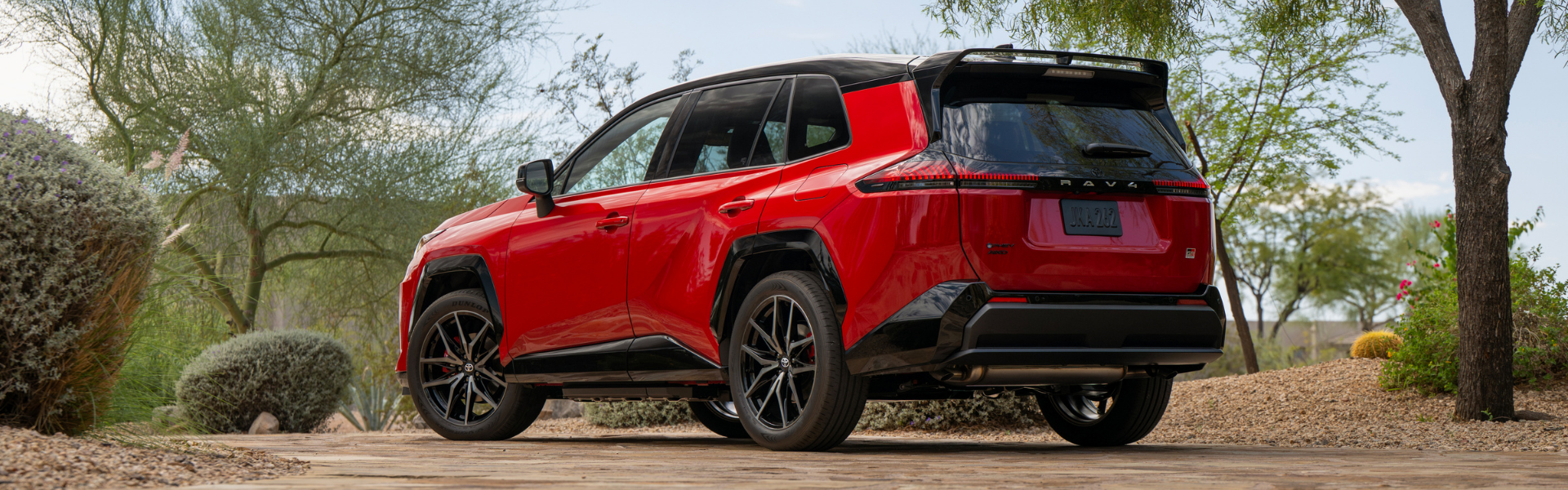 Red 2026 Toyota RAV4 PHEV GR Sport shown from the rear three-quarter angle parked on a desert driveway