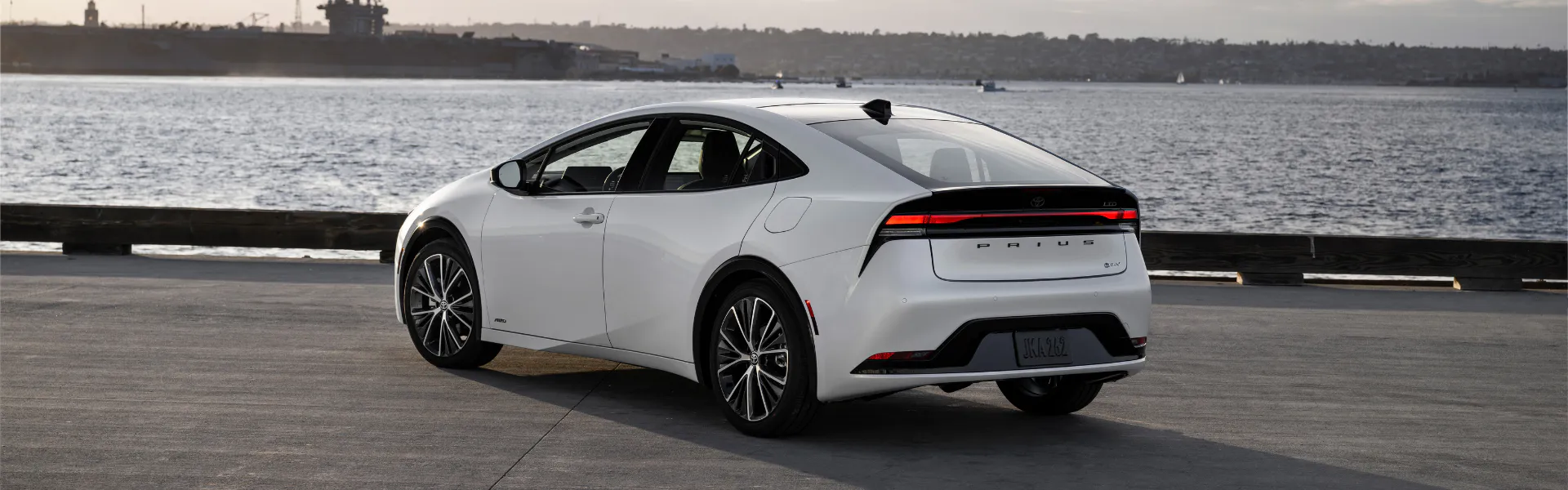 White Toyota Prius parked by the water with rear LED taillight visible