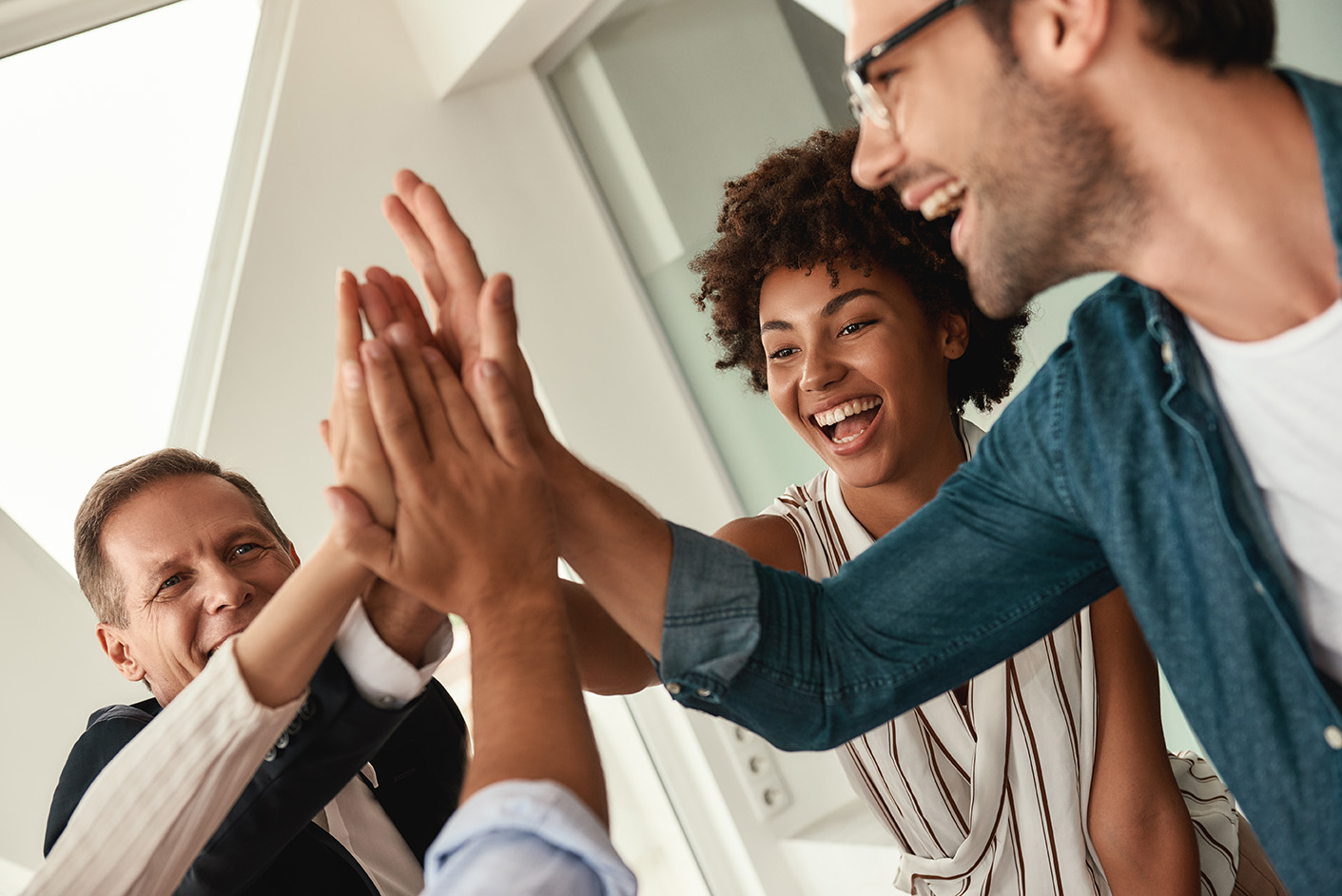 Celebrating success. Business people giving each other high-five and smiling while working together in the modern office. Teamwork