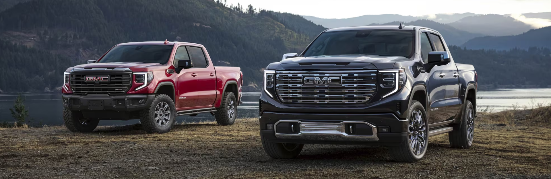 Two 2026 GMC Sierra 1500 trucks sitting near a lake.