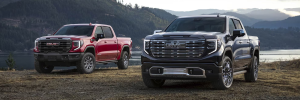 Two 2026 GMC Sierra 1500 trucks sitting near a lake.