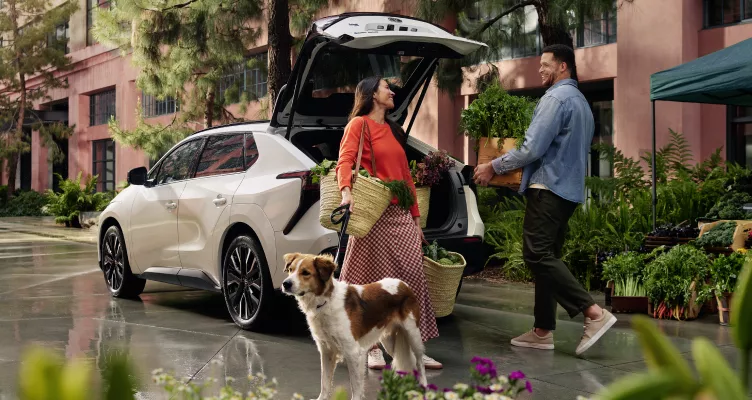 Unknown people and dog near open cargo door of 2026 Toyota bZ i