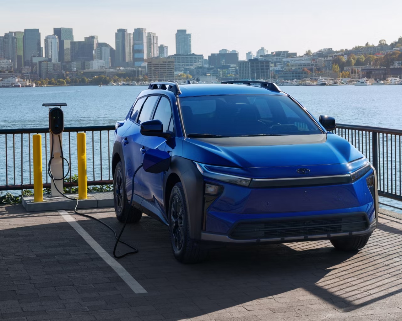 2026 Toyota bZ Woodland plugged into charger and parked near body of water