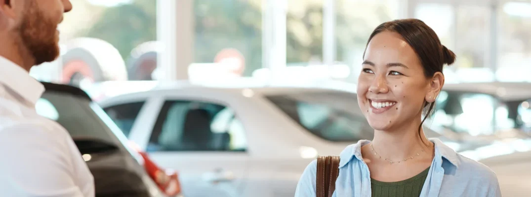 A woman talks to a dealership salesman about buying a Lincoln certified pre-owned vehicle.