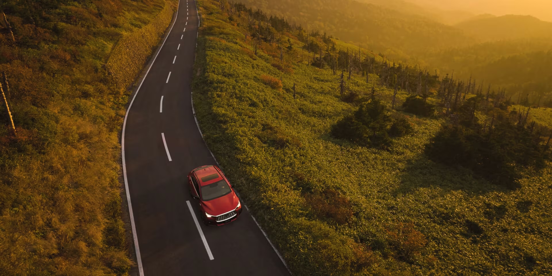 QX55 driving on road surrounded by terrain