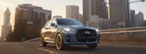2025 INFINITI QX50 driving down road with cityscae