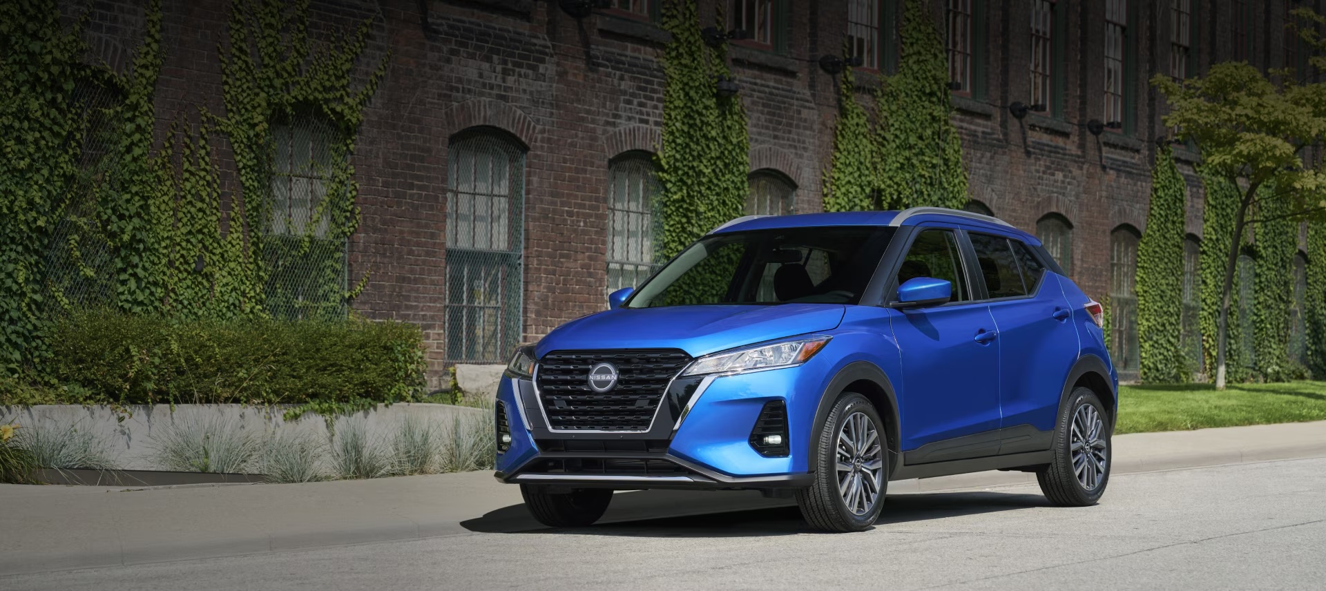 2025 Nissan Kicks Play parked in front of a brick building