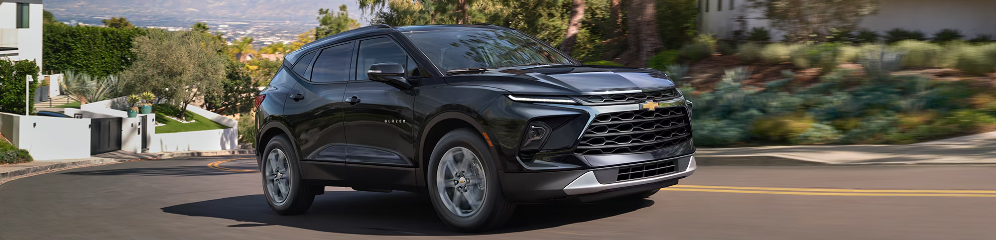 2025 Chevrolet Blazer driving on residential road during the day.